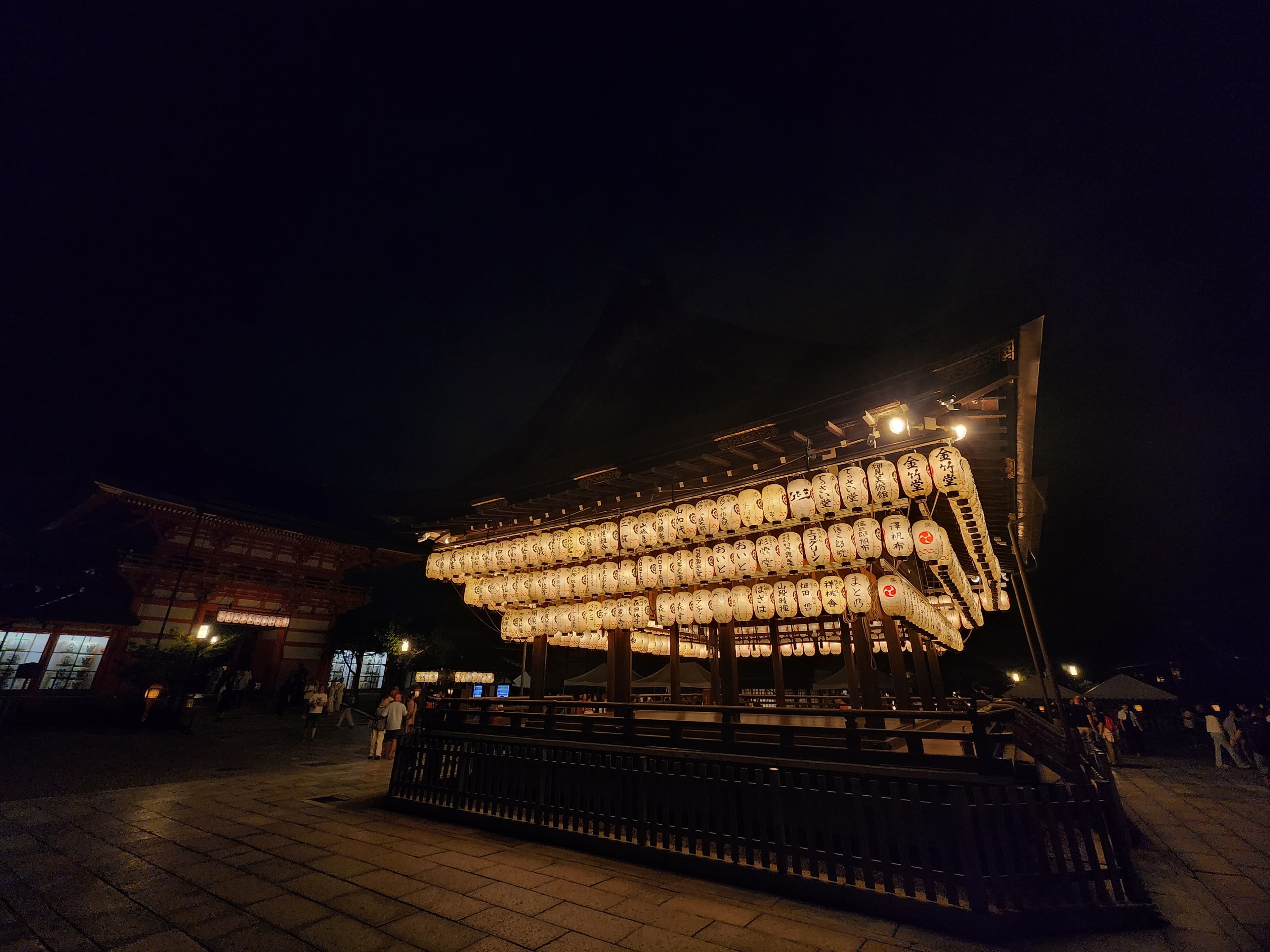 Pabellón japonés iluminado por cientos de linternas de papel blancas con caligrafía durante la noche.