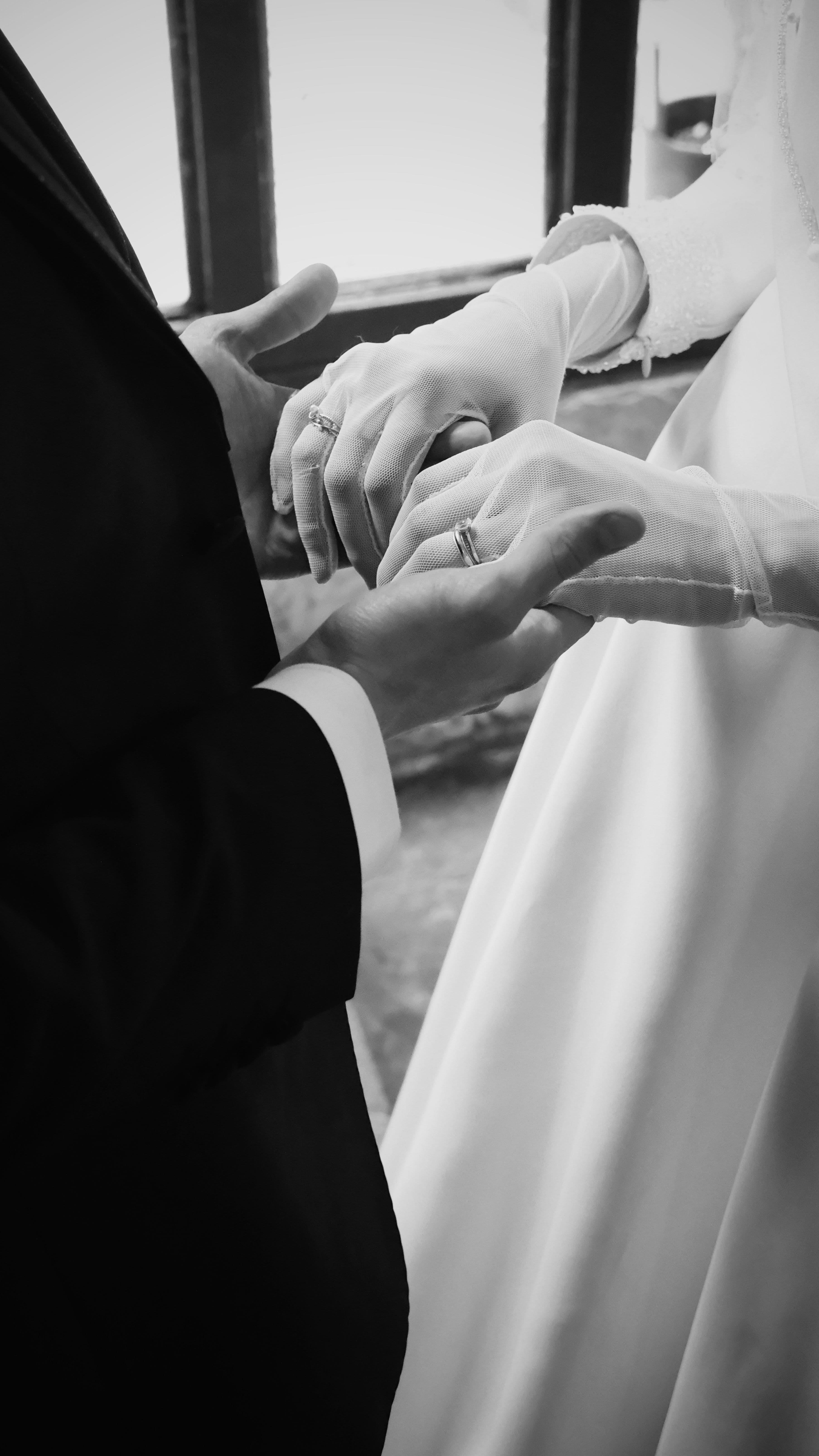 Novios tomados de la mano en blanco y negro, ella con guantes de encaje.